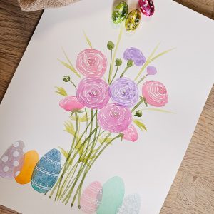 Aquarelle d'un bouquet de renoncules entouré d'œufs nacrés, avec des couleurs acidulées et lumineuses.